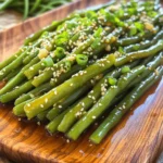 - 1 pound fresh green beans, trimmed - 3 tablespoons honey - 2 tablespoons soy sauce - 3 cloves garlic, minced - 1 tablespoon olive oil - 1 teaspoon sesame oil - Salt and pepper to taste - Sesame seeds for garnish - Chopped green onions for garnish Gathering the right ingredients is key for this dish. The fresh green beans bring a crisp bite. Honey adds sweetness, while soy sauce gives a rich flavor. Garlic packs a punch and makes everything better. Olive oil and sesame oil work well together for cooking. Don’t forget salt and pepper for seasoning. Lastly, sesame seeds and green onions make great garnishes. Make sure your green beans are bright and firm. If you can, buy them from a local market. Fresh ingredients make a big difference in taste. For honey, choose a pure kind for the best flavor. This simple ingredient list lets you create something delicious quickly. 1. Washing and trimming green beans: First, rinse 1 pound of fresh green beans under cool water. This step helps to remove dirt. Then, trim the ends of each bean. You can do this by simply snapping them off or using a knife. 2. Preparing the honey garlic sauce: In a small mixing bowl, combine 3 tablespoons of honey, 2 tablespoons of soy sauce, and 3 minced cloves of garlic. Add 1 tablespoon of olive oil and 1 teaspoon of sesame oil. Whisk everything together until it is smooth and well combined. This sauce brings sweet and savory flavors. 1. Sautéing green beans: Heat a large skillet over medium-high heat. Add the trimmed green beans to the skillet. Sauté them for about 3 to 4 minutes. You want them to brighten in color and soften a little. 2. Adding the sauce and finishing cooking: Pour the honey garlic mixture over the sautéed green beans. Toss the beans to coat them evenly in the sauce. Cook for an additional 5 to 7 minutes. Stir occasionally until the green beans are tender-crisp. The sauce should thicken slightly. Once done, season with salt and pepper to taste. To serve, transfer the green beans to a platter. For a nice touch, sprinkle sesame seeds and chopped green onions on top. This not only adds flavor but also makes the dish look great! Enjoy your savory honey garlic green beans as a side dish or a quick snack. To get the best taste, adjust sweetness and saltiness. If you like it sweeter, add more honey. For a saltier kick, increase the soy sauce. Taste as you go. This way, you can find your perfect balance. Finding the right sauté time is key. Start with medium-high heat. Sauté the green beans for 3-4 minutes until they turn bright. Then, add the honey garlic sauce. Cook for another 5-7 minutes. This will help the beans stay tender but crisp. Pair honey garlic green beans with main dishes for a complete meal. They go well with grilled chicken or fish. You can also serve them with rice for a satisfying side. Garnish with sesame seeds and green onions for a pop of color. {{image_2}} What are some alternatives to soy sauce? If you want a soy sauce substitute, try coconut aminos. It offers a similar taste but is soy-free. You can also use tamari for a gluten-free option. What sweetener options can I use instead of honey? If you need a honey alternative, maple syrup works well. It adds a nice flavor and sweetness. Agave syrup is another option that will not change the dish too much. How can I roast instead of sautéing? Roasting gives the green beans a nice flavor. Preheat your oven to 425°F. Toss the green beans with the honey garlic mix. Spread them on a baking sheet and roast for 15-20 minutes. This method gives you a slightly crispier texture. What spices or herbs can I add? You can add red pepper flakes for some heat. A pinch of ginger gives a nice zing too. Fresh herbs like basil or cilantro can brighten the dish. These additions make the green beans even more exciting. Store your honey garlic green beans in an airtight container. This will keep them fresh. Place the container in the fridge. They will last for up to three days. Before storing, let them cool down. This helps prevent condensation inside the container. To reheat, use a skillet over medium heat. Add a bit of oil to keep them from sticking. Heat for about 3-5 minutes. Stir gently to maintain their crunch. You can also microwave them. Use a covered bowl and heat for 1-2 minutes. Stir halfway through for even warming. I do not recommend freezing honey garlic green beans. Freezing can change their texture. They may become mushy when thawed. If you have to freeze them, place them in a freezer bag. Remove as much air as possible. Use them within a month for the best flavor. How do you make honey garlic sauce from scratch? Making honey garlic sauce is easy. Mix 3 tablespoons of honey, 2 tablespoons of soy sauce, and 3 minced garlic cloves. Add 1 tablespoon of olive oil and 1 teaspoon of sesame oil. Whisk it all together until smooth. Can I add protein to this recipe? Yes, you can add protein. Chicken, shrimp, or tofu work well. Cook the protein first, then add the green beans and sauce. This adds flavor and makes it a full meal. What can I serve with honey garlic green beans? These green beans pair well with rice, chicken, or fish. They also go great with noodles. Their sweet and savory taste complements many dishes. Can I use frozen green beans? You can use frozen green beans. Just thaw them first. Cook them a little longer to get the right texture since they are softer than fresh ones. How can I make this dish spicy? To add heat, mix in red pepper flakes or sriracha. Start with a little, then taste. You can always add more if needed. This gives the dish a nice kick. Are honey garlic green beans healthy? Yes, they are healthy! Green beans are low in calories and high in fiber. The honey adds a bit of sugar, but it’s balanced by the nutrients in the beans. What are the calories per serving? Each serving has about 120 calories. This can vary with added ingredients. It’s a tasty, low-calorie side dish for any meal. This blog shared a simple, flavorful recipe for honey garlic green beans. You learned about ingredients, preparation, and cooking steps. I also offered tips for enhancing flavor and serving suggestions. Variations allow you to customize the dish, while storage info helps keep leftovers fresh. These green beans are easy to make and taste great. Enjoy making this dish as a side or snack!